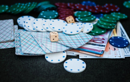 Casino poker chips stack with playing cards, dice and money on green felt backgroundの写真素材