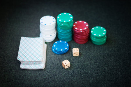 Casino poker chips stack with playing cards, dice on green felt backgroundの写真素材