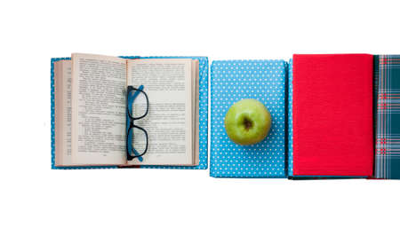 Open textbook, pile of books in colorful covers and apple on white background. Back to school distance home education.の写真素材
