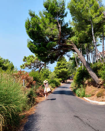 A girl in summer hat on the mountain road on the coast near town Budva in Montenegro, Europe, Adriatic Sea and the Balkan Mountains, beautiful viewの写真素材