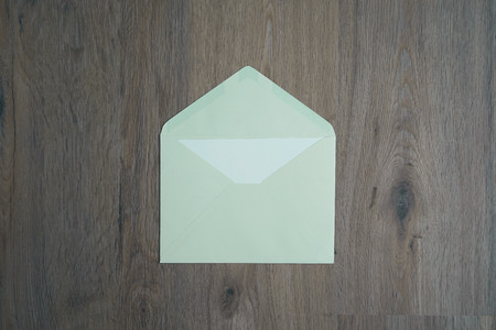 An open green envelope on the wood desk, top view.の写真素材