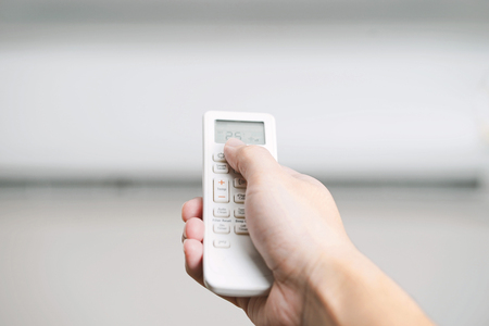 Hand holding remote controller to adjust temperature of air-condition.の写真素材