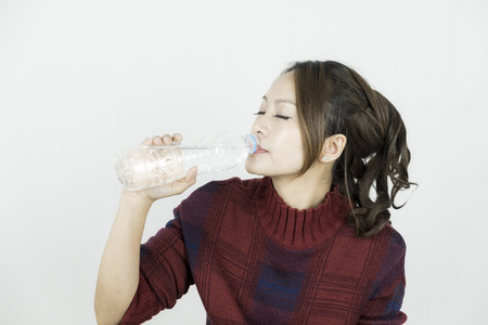 Young attractive beautiful asian woman drinking water from plastic bottle.の写真素材