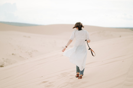 Young female exploring the desert, sandy beach camera.の写真素材