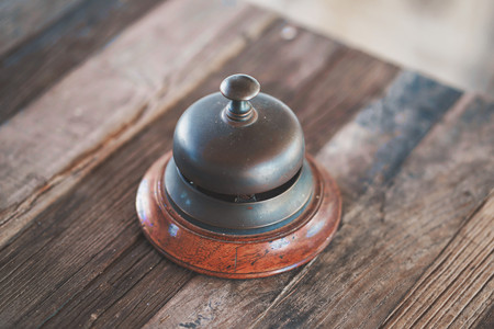 Vintage hotel reception service desk bell on wooden table. Old retro style.の写真素材