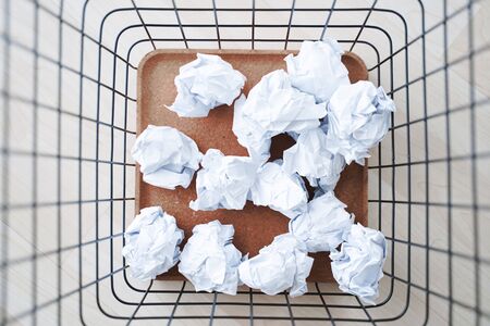 Trash basket and paper crumples. Overflowing waste paper in office garbage bin.