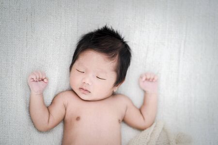 Adorable newborn baby peacefully sleeping on a white blanket, Top view.の写真素材
