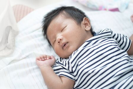 Adorable Asian sleeping, tiny infant healthy sleep with warm wool white blanket at home, baby health care concept.の写真素材