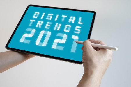 Man hand holding white tablet with Digital Trends 2021 on screen. New trends digital marketing,...