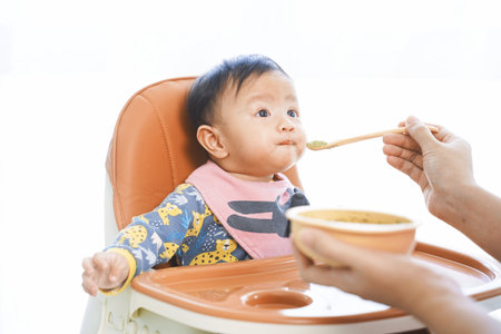 6 months old baby girl eating blend food on a high chair.の写真素材