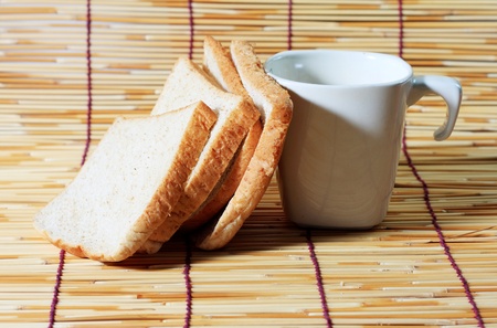 bread and cup on bamboo plate, many slice of bread from whole wheat flour and white cup on bamboo plate.の写真素材