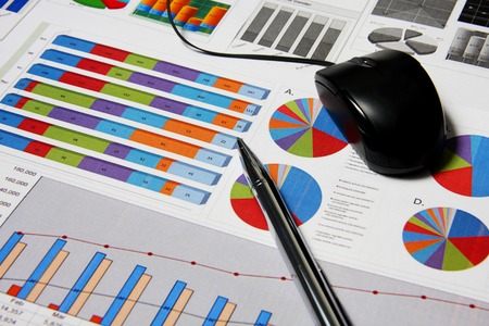 Business finance chart with silver pen and mouse on table.