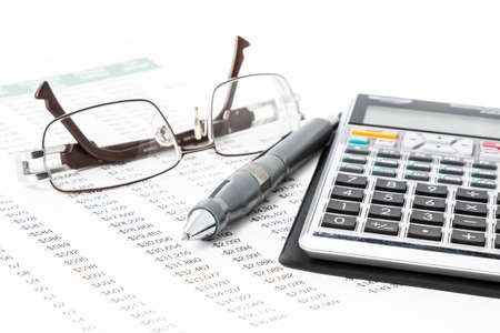 A pen, calculator and glasses on a list of numbers