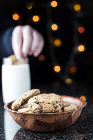 Chocolate chip cookies and milk on a granite table with lights on the backgroundの写真素材