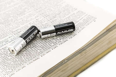 Silver and black batteries on a dictionary opened at energy