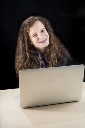 A teenage girl sitting with her laptop at a table