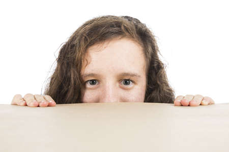A teenage girl peaking over a table's edge isolated on whiteの写真素材