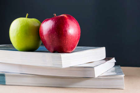 Apples on a pile of books on a table with black backgroundの写真素材