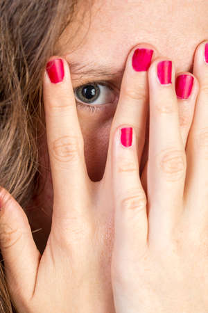 A Teen Peeking thorugh fingers her fingers with red nailsの写真素材