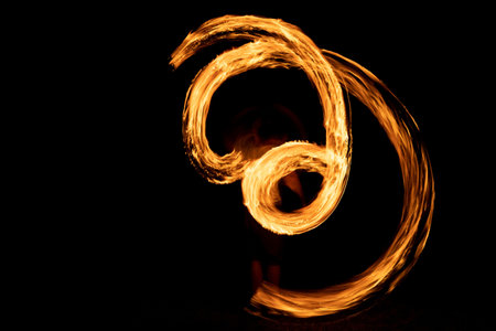 A beautiful shot of a person doing a fire Poi show in the darkの写真素材