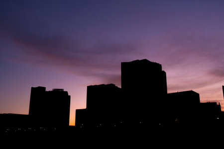 Dawn in the city, vivid purple sky and tall buildings in silhouetteの写真素材