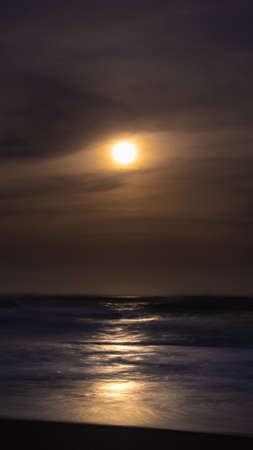 Moonlight reflected on dark ocean at night. Long exposure.の写真素材