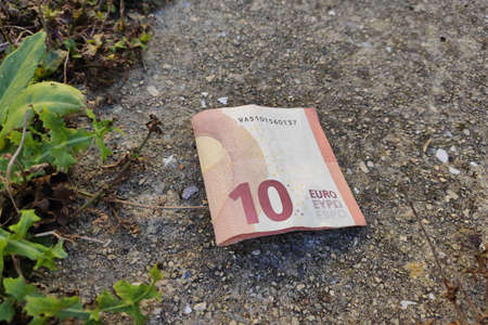 10 Euros folded banknote dropped on pavement in street. Lost money on wet ground.の写真素材