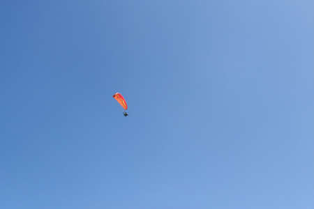 Powered paragliding - paraglider with red parachute against a blue sky.の写真素材