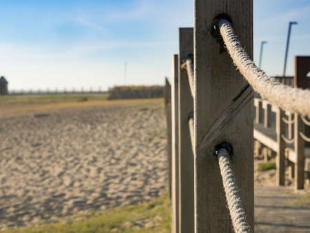 Rustic wooden rope fence on path leading to beach. Sandy beach in summer.の写真素材