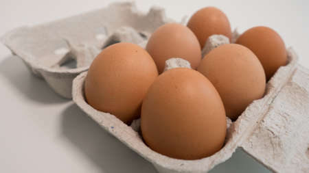 Carton of six eggs on white table. close up