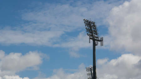 Stadium floodlight against blue sky with white clouds