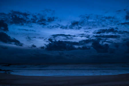 Dark moody clouds over ocean at dusk on beach in winterの写真素材