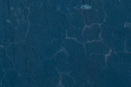Old, blue painted concrete wall with cracks in plaster and weathering. Grunge background texture.