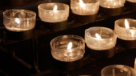 Rows of burning lit candles tea lights in Catholic Christian Church