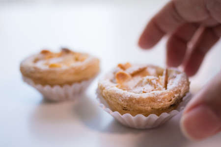Portuguese Almond Pastry Tart being picked up from a white table.の写真素材