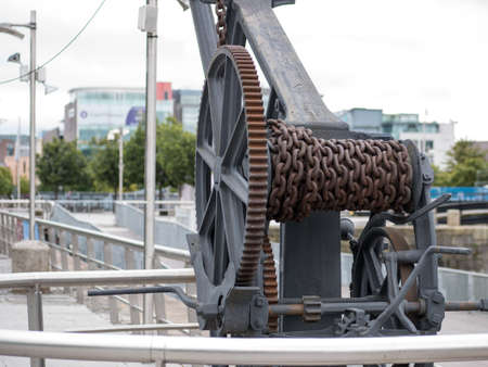 Old, rusted 19th century lifting and unloading winch with chain at George Dock in Dublin, Ireland.のeditorial素材
