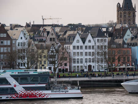 Typical German architecture buildings and restaurants on the banks of the River Rhine in Cologne, Germany. Cruise ship in foreground.のeditorial素材