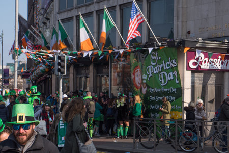 Crowds outside Irish pub in Dublin, Ireland on St. Patrick's Day with Irish flags and American flag.のeditorial素材