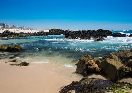 Beautiful rocky beach on sunny day with clear blue water and cloudless sky in Vila do Conde, Portugalの写真素材