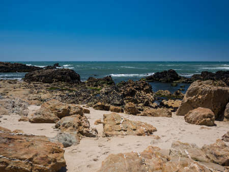 Rocky beach in summer with clear blue water and cloudless sky in Vila do Conde, Porto, Portugalの写真素材