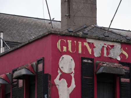 Old, abandoned, Irish pub with peeling Guinness paint and dirty window canopiesのeditorial素材