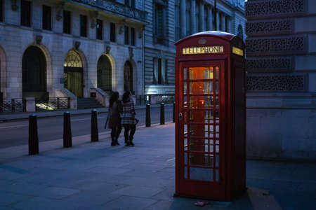 Famous red telephone booth in London England at night, illuminated inside.