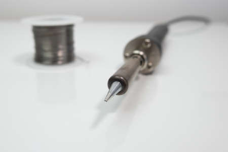 Soldering iron tip and solder wire. Close up, shallow depth of field with blurred background.