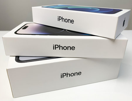Apple iPhones in boxes, stacked on white desk. iPhone 14 Pro, 12 and XR.のeditorial素材