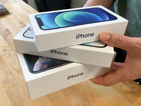 Woman holding a stack of Apple iPhones in boxes. iPhone 14 Pro, 12 and XR.のeditorial素材
