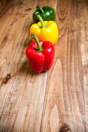 Colored bell peppers on wooden tableの写真素材