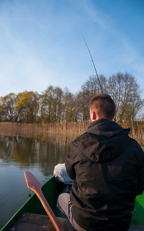 Angler fishing with rod on boatの写真素材