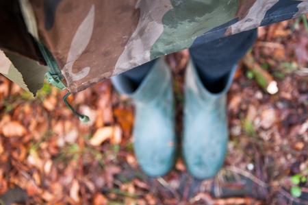 Woman in raincoat and waders standing on autumn leavesの写真素材