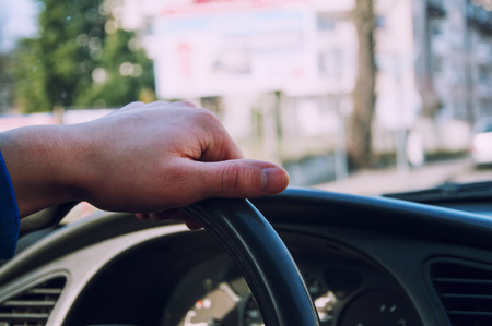 Hands of a driver on steering wheel of a car in the cityの写真素材