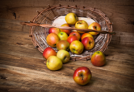 Apples in basket on wooden backgroundの写真素材